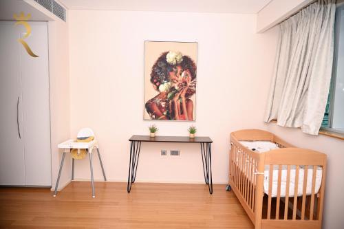 a room with a crib and a painting on the wall at Luna Breeze - Elegant 2BR Apartment with Beach Access, Near Al Raha Beach in Abu Dhabi