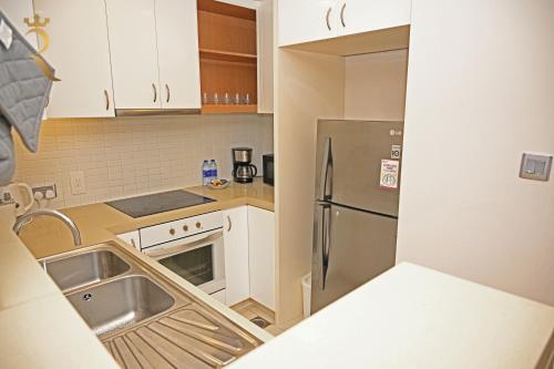 a kitchen with white cabinets and a stainless steel refrigerator at Your 2BR Luna Retreat with Beach Access in Al Rahba in Abu Dhabi