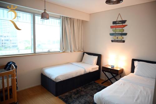 a small bedroom with two beds and a window at Luna Breeze - Elegant 2BR Apartment with Beach Access, Near Al Raha Beach in Abu Dhabi