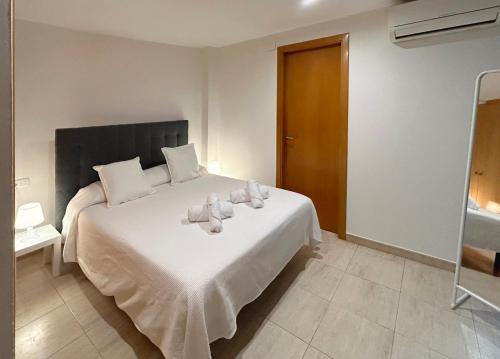 1 dormitorio con 1 cama blanca grande con almohadas blancas en M1 Céntrico y con balcón, en Terrassa