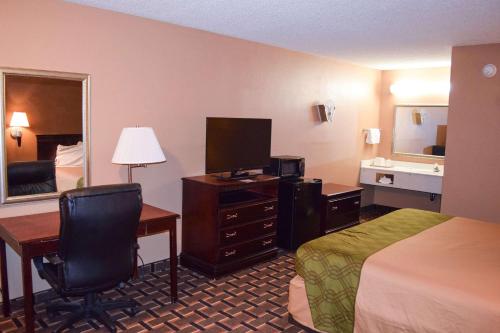 Cette chambre comprend un lit, un bureau et une télévision. dans l'établissement Richburg Inn, à Richburg