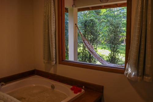 a bath tub in a bathroom with a window at Montanhas Do Visconde in Visconde De Maua