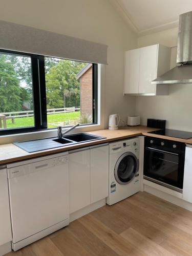 a white kitchen with a sink and a dishwasher at Stunning 2 bedroom Guesthouse in Tamahere