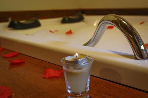a candle in a glass in front of a bath tub at Montanhas Do Visconde in Visconde De Maua