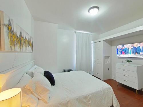 um quarto com uma cama branca e uma televisão de ecrã plano em Elegant 3Br Apt Yankee stadium em Melrose