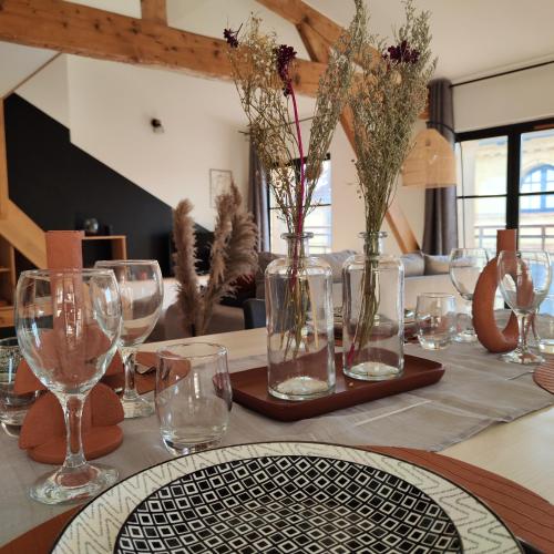 une table avec des verres et des vases avec des fleurs dans l'établissement Le Notre-Dame - Centre-ville, à Montauban