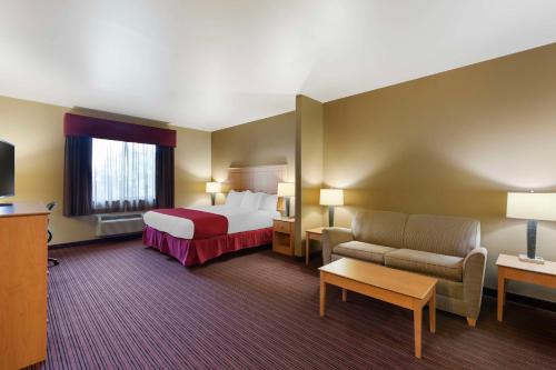 シドニーにあるBest Western Golden Prairie Inn and Suitesのベッドとソファ付きのホテルルーム