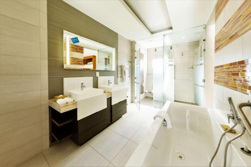 a bathroom with a tub and a sink and a bath tub at DoubleTree by Hilton Cape Town Upper Eastside in Cape Town
