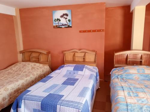 two beds in a room with orange walls at Hostal Puerto Alegre in Copacabana