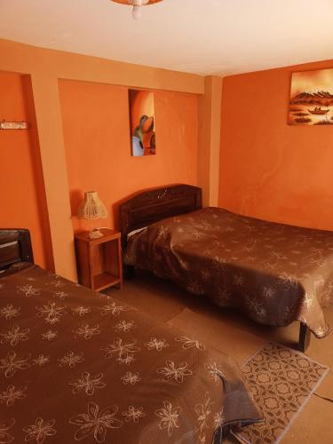 two beds in a room with orange walls at Hostal Puerto Alegre in Copacabana