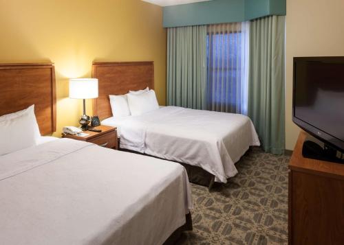 a hotel room with two beds and a flat screen tv at Homewood Suites by Hilton Irving-DFW Airport in Irving