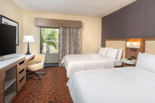 a hotel room with two beds and a flat screen tv at Hampton Inn & Suites San Clemente in San Clemente