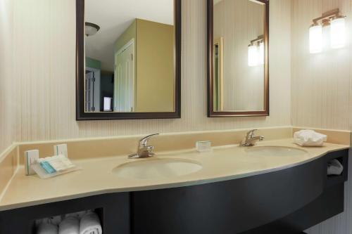 a bathroom with two sinks and two mirrors at Hilton Garden Inn Tallahassee in Tallahassee