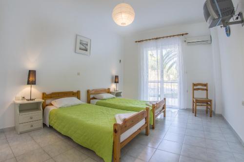 - une chambre avec 2 lits et une fenêtre dans l'établissement Olive Grove Apts, à Lithakia