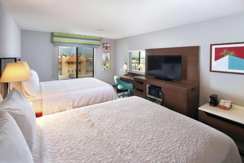 a hotel room with two beds and a flat screen tv at Hampton Inn & Suites Tucson East in Tucson