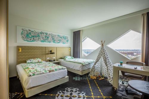 a hotel room with two beds and a desk and windows at Hilton Amsterdam Airport Schiphol in Schiphol