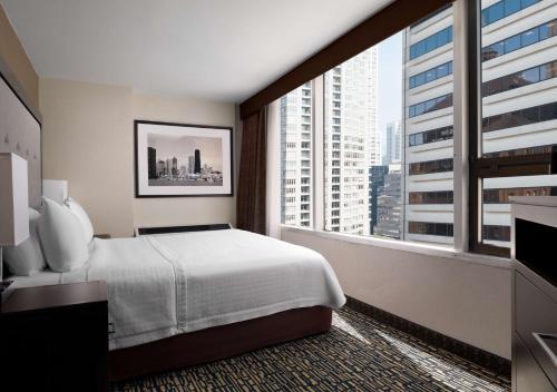 シカゴにあるHomewood Suites by Hilton Chicago Downtown - Magnificent Mileのベッドと大きな窓が備わるホテルルームです。