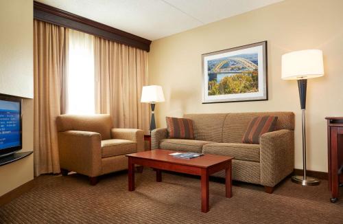 a living room with a couch and chairs and a tv at DoubleTree Suites by Hilton Hotel Cincinnati - Blue Ash in Sharonville
