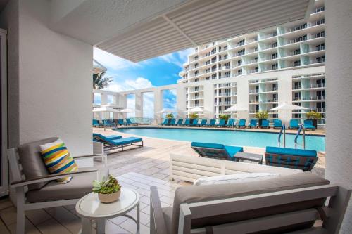 a patio with a pool and chairs and a building at Conrad Fort Lauderdale Beach in Fort Lauderdale