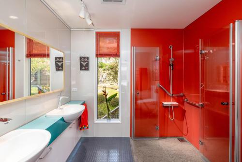 a red bathroom with a sink and a shower at The Bolthole - Charteris Bay Holiday Home in  Lyttelton