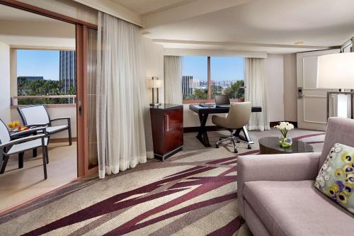a living room with a couch and a table with a desk at Hilton Long Beach Hotel in Long Beach