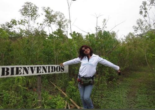 a woman is standing next to a sign at La Cachuela Lodge. 