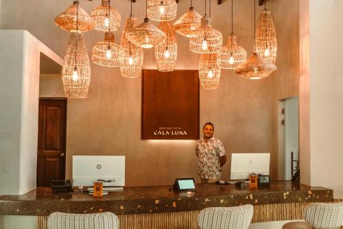 a man standing behind a bar with chandeliers at Cala Luna Boutique Hotel & Villas in Tamarindo