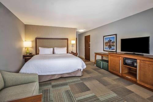 a hotel room with a bed and a flat screen tv at Hampton Inn Southfield/West Bloomfield in Farmington Hills