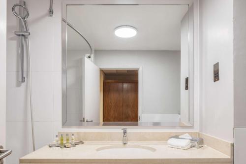 baño con lavabo y espejo grande en DoubleTree by Hilton Newbury North en Newbury