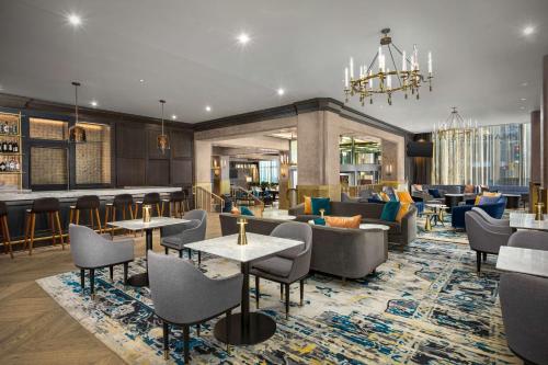 um átrio do hotel com mesas e cadeiras e um bar em The Marquette Hotel, Curio Collection by Hilton em Minneapolis