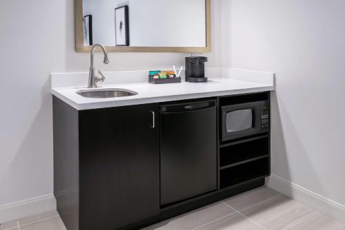 eine Küche mit einer Spüle und einer Mikrowelle in der Unterkunft Embassy Suites by Hilton Houston West - Katy in Houston