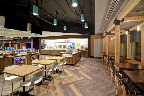 a restaurant with wooden tables and chairs and a counter at Tru By Hilton Raleigh Durham Airport in Morrisville