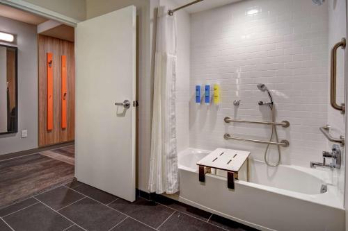 a bathroom with a tub and a shower with a bench at Tru By Hilton Raleigh Durham Airport in Morrisville