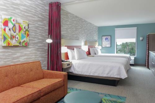 Home2 Suites By Hilton Fort Collins في فورت كولينز: غرفه فندقيه بسرير واريكه