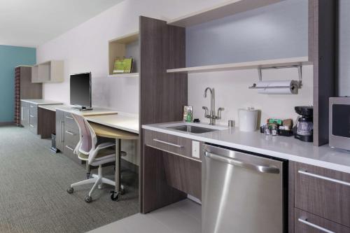 a kitchen with a sink and a desk with a computer at Home2 Suites By Hilton Fort Collins in Fort Collins