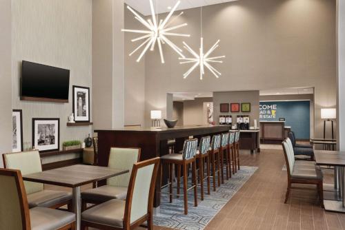 a restaurant with tables and chairs and a bar at Hampton Inn Brooklyn Park in Brooklyn Park