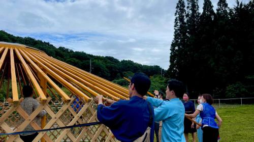 a group of people standing around a wooden structure at miniモンゴルキャンプ場 in Gujo