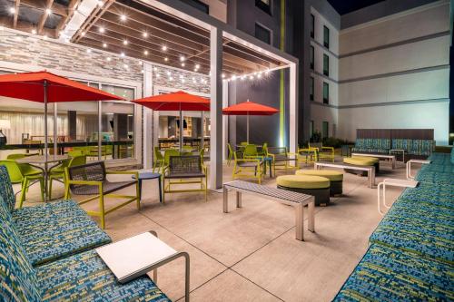 a restaurant with tables and chairs and red umbrellas at Home2 Suites By Hilton Brunswick in Brunswick
