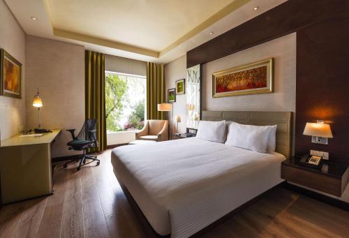 a hotel room with a large bed and a desk at DoubleTree by Hilton Gurugram Baani Square in Gurgaon