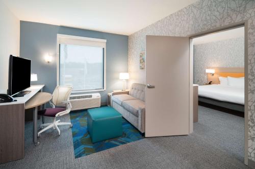 a hotel room with a bed and a desk with a computer at Home2 Suites By Hilton Brunswick in Brunswick