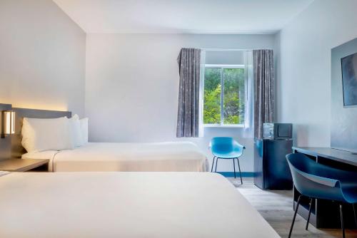 a hotel room with two beds and a desk and a window at Motel 6 Bethel, CT - Danbury in Bethel