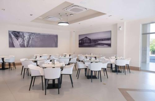 een eetkamer met witte tafels en witte stoelen bij Super 8 by Wyndham Manzanillo 