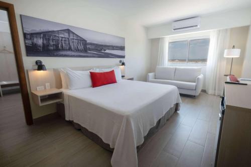 a hotel room with a large bed and a chair at Super 8 by Wyndham Manzanillo in Pepillo Salcedo