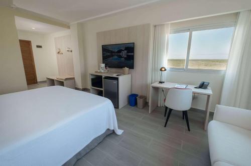 a bedroom with a bed and a desk and a window at Super 8 by Wyndham Manzanillo in Pepillo Salcedo
