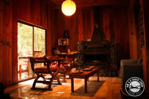 sala de estar con mesa y chimenea en River Lodge, en Pucón