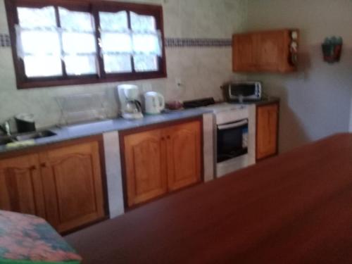 a kitchen with wooden cabinets and a sink and a window at La rana alquiler temporal in Reyes