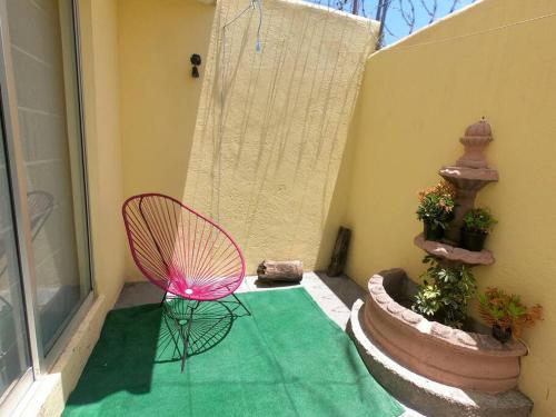 a pink chair sitting on a porch with a green rug at Casa llena de vida y estilo en un conjunto con vigilancia céntrico en Puebla in Puebla