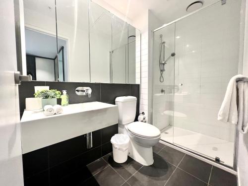 ein Bad mit einem WC, einem Waschbecken und einer Dusche in der Unterkunft Readyset Apartments at Manhattan in Melbourne