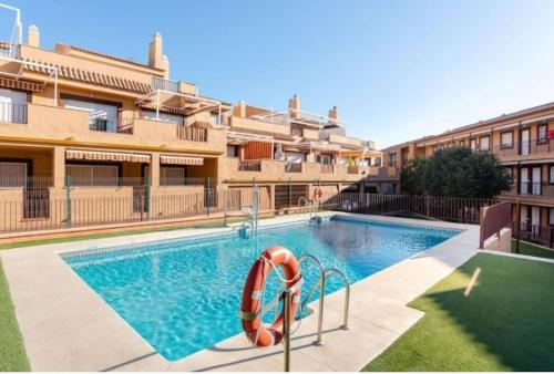 a swimming pool with a life preserver in front of a building at Ático con gran terraza a 50 metros de la playa de Casares in San Luis de Sabinillas