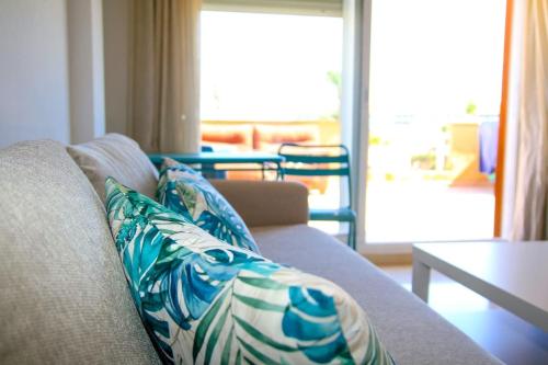 a living room with a couch with blue and white pillows at Ático con gran terraza a 50 metros de la playa de Casares in San Luis de Sabinillas